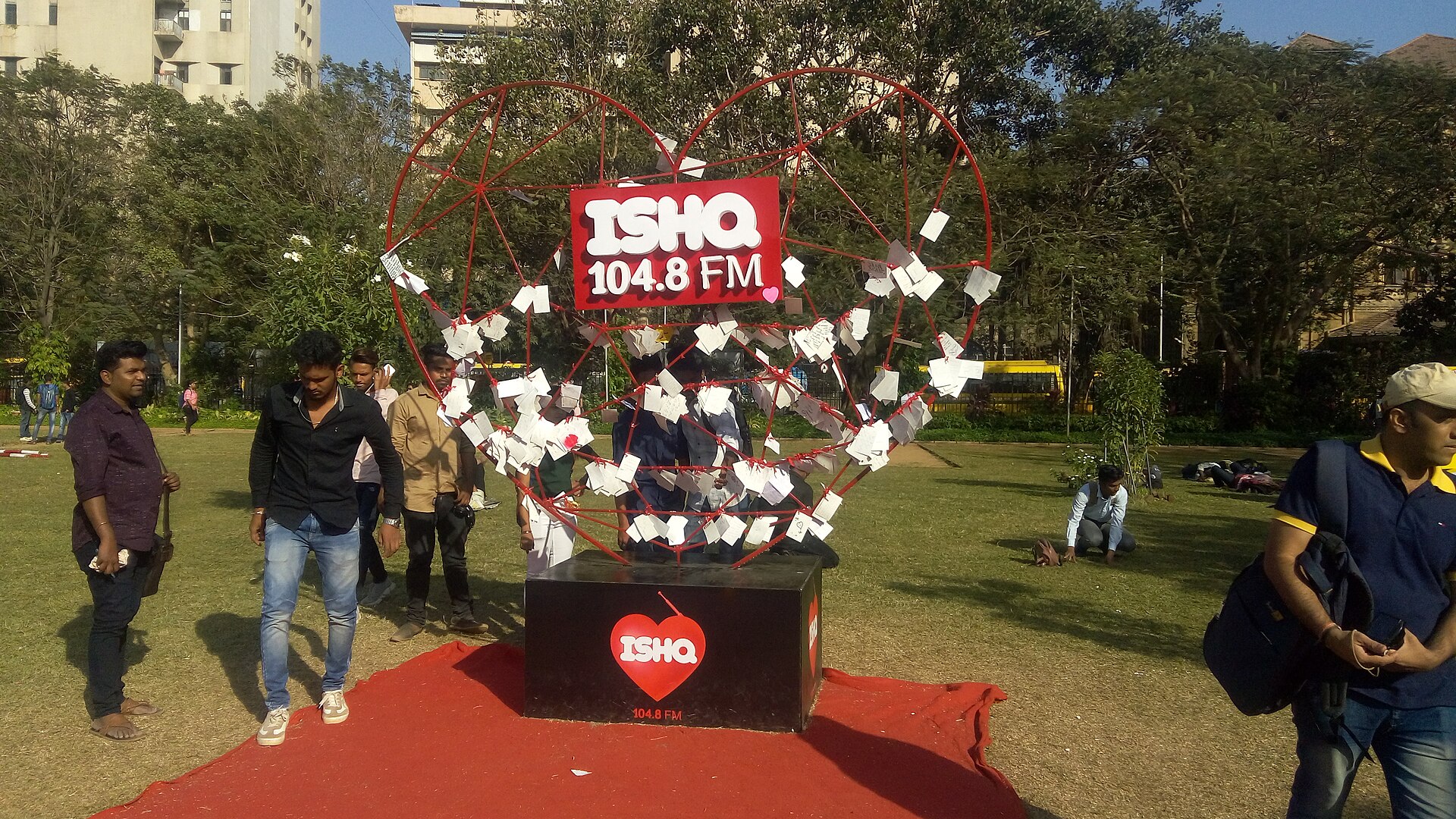 An Ishq FM event with a large wheel and falling paper pieces outdoors.